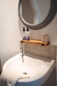 La salle de bains est pourvue d'un lavabo blanc et d'un miroir. dans l'établissement Unique 2 Bedroom Cottage in Fittie (Footdee), à Aberdeen 31 autres photos