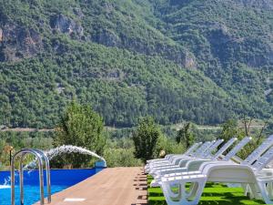 una fila de sillas blancas sentadas junto a una piscina en Hotel & Restaurant Ada en Gusinje