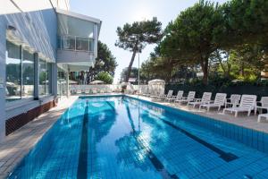 a swimming pool with chairs and a house at Hotel Sahara in Milano Marittima