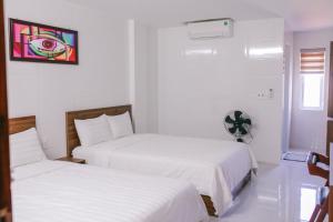 2 łóżka w pokoju z białymi ścianami w obiekcie Vagibi Hotel w mieście Dong Hoi
