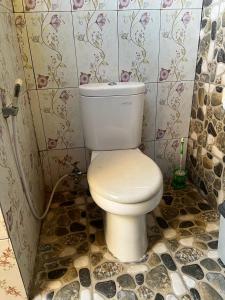 a bathroom with a toilet in a tiled room at Banana cottages in Gili Air