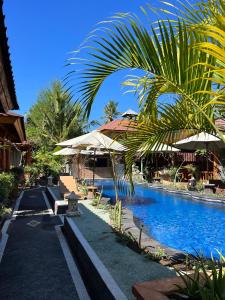 a resort swimming pool with chairs and umbrellas at Banana cottages in Gili Air