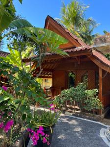 a house with a bunch of flowers in front of it at Banana cottages in Gili Air