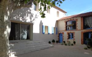 - un bâtiment blanc avec une porte bleue et des escaliers dans l'établissement Domaine Les Rivales, à Cavaillon