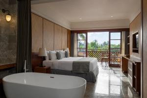 a hotel room with a tub and a bed and a balcony at Adiwana Bisma in Ubud