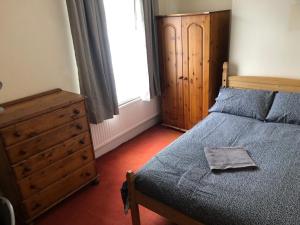 a bedroom with a bed and a dresser and a window at 4-Bedroom House Close to Barnsley Centre in Barnsley