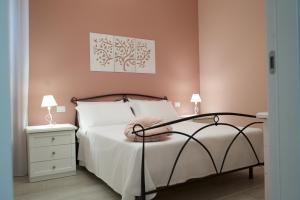 ein Schlafzimmer mit einem Bett mit einer rosa Wand in der Unterkunft Agapanthus Holiday Home in Noto