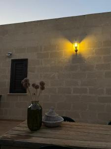 un vase sur une table avec une lumière sur un mur de briques dans l'établissement La finestra a tramontana, à Favignana