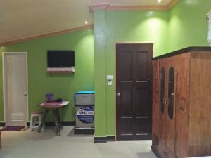 a room with a green wall and a door and a table at Villa Corrales Homestay in Mambajao