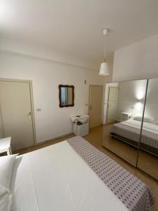 a bedroom with a large white bed and a mirror at Hotel Naviglio in Marina di Pietrasanta