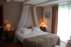 a bedroom with a white bed with a canopy at Les Chambres de Kerzerho in Erdeven +8 photos