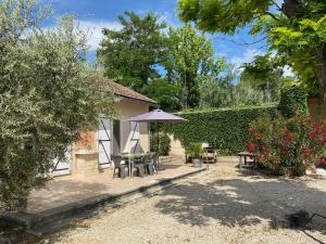 un patio con mesa y sombrilla en Les Célestins - Villa en Provence, en Carpentras