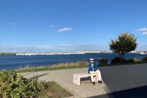 Eine Statue eines Mannes, der auf einer Bank neben dem Wasser sitzt. in der Unterkunft Haus Windböe, Wohnung 6 in Duhnen
