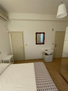 a bedroom with a white bed and a mirror at Hotel Naviglio in Marina di Pietrasanta