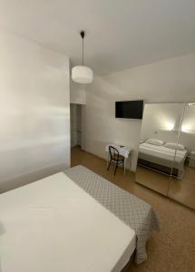 a white bedroom with a bed and a mirror at Hotel Naviglio in Marina di Pietrasanta