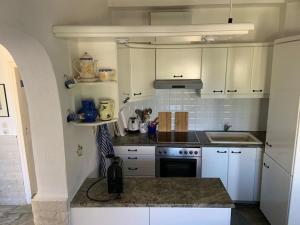 a kitchen with white cabinets and a stove top oven at Familienfreundliches Fischerhaus am Strand in Porto Heli