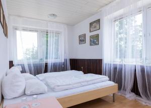 a bedroom with a bed with white sheets and a window at Ringhaus - Home of Silver Arrows in Nürburg