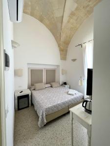 een witte slaapkamer met een bed en een tafel bij Masseria Mazzetta Salento Corte del Falconiere B&B in San Pancrazio Salentino