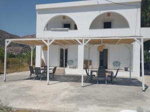 une maison blanche avec une table et des chaises dans l'établissement Mini Villas Avra, à Keratokampos