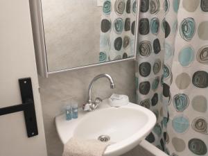 a bathroom sink with a mirror and a shower curtain at Mini Villas Avra in Keratokampos