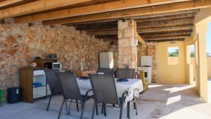 une table et des chaises dans une pièce avec un mur en pierre dans l'établissement Villa Sophie, à La Canée