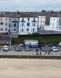 a parking lot with cars and a bus and buildings at Eastcliffe Penthouse, 2 beds & bathrooms with parking in Cleethorpes