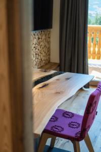 a wooden table and a purple chair in a room at Chalet am Wiesenweg in Chiusa