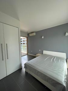 a bedroom with a white bed and a sliding door at YooBulgaria-Obzor SP apartments in Obzor