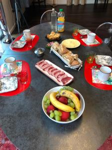 a table topped with plates of food and a bowl of fruit at Chez Cathy et Léo in Dinan