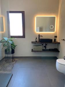 een badkamer met een wastafel, een toilet en een spiegel bij Villetta San Bartolomeo in Monopoli