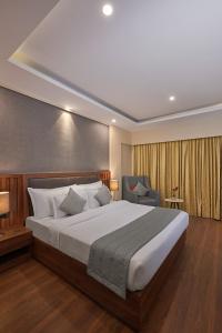 a bedroom with a large bed and a chair at Southern Star,Bangalore in Bangalore