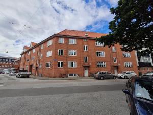 un gran edificio de ladrillo con coches estacionados frente a él en Marbækvej (ID 030), en Esbjerg