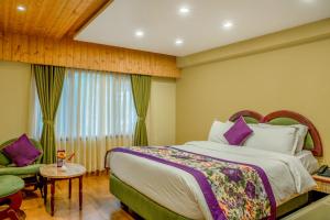um quarto com uma cama grande e uma janela em Mount Conifer Suites & Spa em Darjeeling