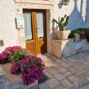 une porte d'une maison avec des fleurs devant elle dans l'établissement La tana degli Incerti, à Alberobello