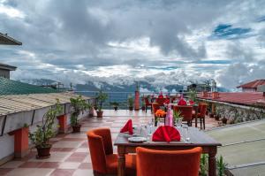 um restaurante com uma mesa e cadeiras numa varanda em Mount Conifer Suites & Spa em Darjeeling