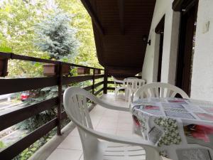 a porch with white chairs and a table and a tree at Charlie Vendégház,emelet 8 fős,100m2-es apartman in Siófok