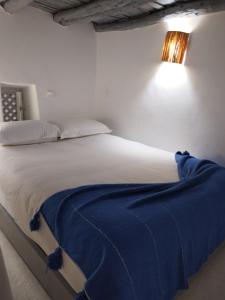 a bedroom with a bed with a blue blanket on it at RIAD MAROSKO in Essaouira