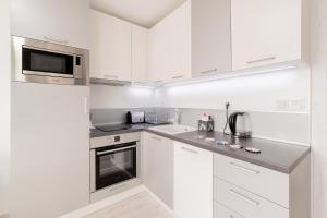 a white kitchen with white cabinets and a microwave at Moderna Apartment in Burgas City