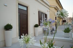 einen Balkon mit Tür, Stühlen und Blumen in der Unterkunft Agapanthus Holiday Home in Noto