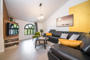 a living room with a black leather couch and a table at Sunset Garden apartment with private pool in Vrsi