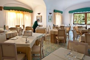 a restaurant with tables and chairs and a person in the background at Hotel Parco Smeraldo Terme in Ischia
