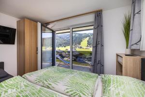 ein Schlafzimmer mit einem Bett und einem großen Fenster in der Unterkunft Fischis Alpen Appartements in Flachau