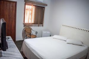 a bedroom with a bed and a chair and a window at Galeria Hotel Pousada in Jaguariúna