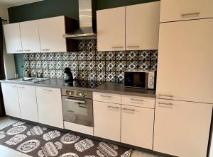 a kitchen with white cabinets and a microwave at Happy Duplex in Jalhay