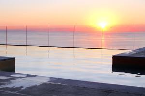 サント・ステーファノ・ディ・カマストラにあるDAMMUSO private villa with infinity pool & seaviewの夕日を背景に水のプール