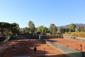 un groupe de personnes jouant au tennis sur un court de tennis dans l'établissement Tennis Rocchette Resort, à Castiglione della Pescaia