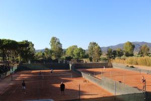 a group of people playing tennis on a tennis court at Tennis Rocchette Resort in Castiglione della Pescaia
