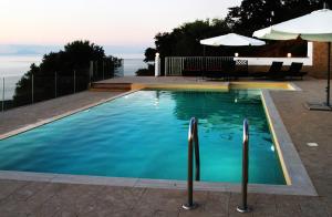 piscina con acqua blu e ombrellone di DAMMUSO private villa with infinity pool & seaview a Santo Stefano di Camastra