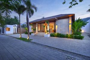 a house with palm trees and a brick driveway at Kabila Villas in Kuta Lombok