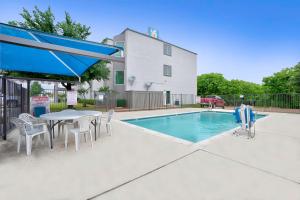 a swimming pool with a table and chairs next to a house at Motel 6-Benbrook, TX - Fort Worth in Benbrook